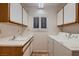 This is a laundry room with a window with shutters, cabinets, a sink, and a white washer and dryer at 8613 Linderwood Dr, Las Vegas, NV 89134