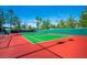 Well-maintained tennis court with a bright red surface and green playing area surrounded by trees at 8613 Linderwood Dr, Las Vegas, NV 89134
