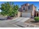 Two-story home with tan stucco, three-car garage, and mature shade tree in front yard at 9065 W Torino Ave, Las Vegas, NV 89148
