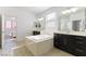 A well-lit bathroom features double sinks, a soaking tub, and tile floors at 10742 Cowlite Ave, Las Vegas, NV 89166