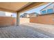 Covered patio featuring brick pavers, overlooking a walled yard with neighboring houses in the background at 10851 Hanwicke Harbor Ave, Las Vegas, NV 89166