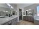 Bright bathroom featuring dual sinks, quartz countertops, framed mirrors and a glass walk-in shower at 11621 La Mirago Pl, Las Vegas, NV 89138
