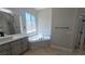 Bright bathroom featuring dual sinks, quartz countertops, framed mirrors and a soaking tub at 11621 La Mirago Pl, Las Vegas, NV 89138