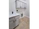 Functional laundry room featuring a sink, gray cabinets, and space for laundry appliances at 11621 La Mirago Pl, Las Vegas, NV 89138