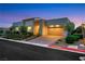 Modern home exterior with a two-car garage, desert landscaping, and well-lit entryway at 11895 Skyline Arch Ct, Las Vegas, NV 89138