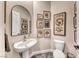 Elegant powder room featuring a pedestal sink, black framed mirror, and framed vintage art prints at 125 Mirage View Dr, Henderson, NV 89011