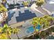 Backyard view of a home with solar panels, a pool, and spa, nestled amongst mature palm trees, offering a private oasis at 1316 Eagle Meadow Ct, Las Vegas, NV 89123