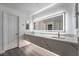 A modern bathroom is brightened by a quartz countertop, twin sinks, a large mirror and integrated lighting at 1316 Eagle Meadow Ct, Las Vegas, NV 89123