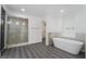This modern bathroom features a sleek soaking tub, glass-enclosed shower, and stylish gray wood-look floors at 1316 Eagle Meadow Ct, Las Vegas, NV 89123