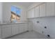 Bright laundry room features white cabinets, quartz countertops, and tile floor at 1316 Eagle Meadow Ct, Las Vegas, NV 89123
