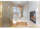 Bright primary bathroom with soaking tub, shower, and fireplace with exterior views at 1933 Davina St, Henderson, NV 89074