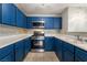 Well-lit kitchen featuring vibrant blue cabinets, tile floors, stainless steel appliances, and practical counter space at 350 S Durango Dr # 108, Las Vegas, NV 89145