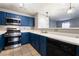This is a well lit kitchen with blue cabinets, stainless steel appliances, and a view into an adjacent room at 350 S Durango Dr # 108, Las Vegas, NV 89145