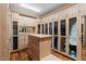 Expansive walk-in closet with custom wood cabinetry, glass shelving, drawers, and an island at 360 E Desert Inn Rd # 1901, Las Vegas, NV 89109