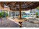 Unique patio space with thatched umbrella and custom stamped concrete near the backyard pool at 3832 Alder Creek Ct, North Las Vegas, NV 89032