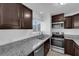 Well-lit kitchen with stainless steel appliances, granite countertops, and dark wood cabinets at 5029 Spencer St # D, Las Vegas, NV 89119