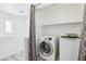 A modern laundry room with washer, dryer, and overhead shelving at 7331 Carrot Ridge St, Las Vegas, NV 89139
