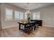 Dining area features a rustic dining table, a chandelier, large windows, and hardwood flooring at 7416 Deschutes Cir, Las Vegas, NV 89129