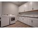 Bright laundry room featuring wood floors, modern appliances, and plenty of white cabinet storage at 7416 Deschutes Cir, Las Vegas, NV 89129