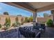 Relaxing covered patio featuring paved flooring, comfortable seating, and landscaped backyard with desert plants at 7416 Deschutes Cir, Las Vegas, NV 89129
