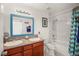 Bathroom featuring dual sinks, a shower-tub combo, a large framed mirror and tiled walls at 7736 Foredawn Dr, Las Vegas, NV 89123