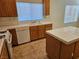 Bright kitchen featuring tile counters, an island, wooden cabinetry, and modern appliances at 7849 Blue Brook Dr, Las Vegas, NV 89147