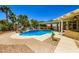 Expansive backyard featuring a pristine pool with a slide, covered patio, and lush palm trees, ideal for relaxation at 8078 Leather Harness St, Las Vegas, NV 89131