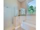 Bright bathroom featuring a walk-in shower, tub, and a large window at 8078 Leather Harness St, Las Vegas, NV 89131