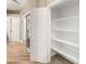 Hallway with wood-look flooring with access to multiple storage and closet spaces with white doors at 8100 Lake Hills Dr, Las Vegas, NV 89128