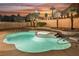 A kidney-shaped pool and hot tub are bordered by desert landscaping and string lights creating a relaxing backyard at 8401 Airmont Ct, Las Vegas, NV 89128