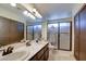 Bright bathroom featuring double sinks, framed mirror, walk-in shower, and tile flooring at 982 Flapjack Dr, Henderson, NV 89014
