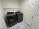 Convenient laundry area featuring black appliances and practical shelving for storage at 10201 Premia Pl, Las Vegas, NV 89135