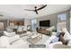 Staged living room flows into the kitchen and dining area with lots of natural light, stylish furnishings, and a ceiling fan at 10201 Premia Pl, Las Vegas, NV 89135