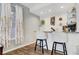 Bright bar area featuring granite countertops, white cabinets, stylish barstools, and a window with charming floral curtains at 2016 Catalina Marie Ave, Henderson, NV 89074