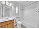Bright bathroom featuring a wood vanity, toilet, and tub/shower combination with white tiles at 2432 Granada Bluff Ct, Las Vegas, NV 89135