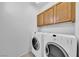 Practical laundry room with modern washer and dryer set and overhead cabinets for storage at 2432 Granada Bluff Ct, Las Vegas, NV 89135