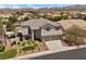 Aerial view showcasing a two-story home with a three-car garage, well-kept lawn, and desert landscaping at 2647 Hourglass Dr, Henderson, NV 89052
