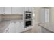 Bright kitchen features stainless steel double oven, white cabinetry, and granite countertops at 2647 Hourglass Dr, Henderson, NV 89052