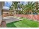 Beautiful backyard featuring artificial grass, mature palm trees, and a covered patio area for outdoor enjoyment at 2679 Regency Cove Ct, Las Vegas, NV 89121