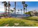 Community pool area surrounded by palm trees and lush green grass at 3318 N Decatur Blvd # 2129, Las Vegas, NV 89130
