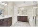 A bright bathroom with a white tub, dark cabinets, double sinks, and a large mirror with vanity lighting at 3638 Via Messina, Henderson, NV 89052