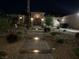 Beautifully landscaped front entrance with a lit stone walkway and custom wrought iron gate at night at 3955 W Jo Rae Ave, Las Vegas, NV 89141