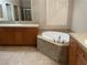 Bathroom featuring a large tub, double sinks, wood cabinetry and tile floor at 4121 Erinbird Ave, North Las Vegas, NV 89084