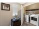 Functional laundry room with washer, dryer, storage shelves, and a decorative plant at 44 Moon Hill Dr, Henderson, NV 89011