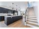 Modern kitchen with island and breakfast bar, stainless appliances, dark cabinets, and staircase at 529 Fork Mesa Ct, Henderson, NV 89015