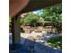 Backyard patio with a stone fire pit, seating, and lush greenery at 5516 Coyote Falls Ct, Las Vegas, NV 89131
