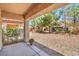 Covered back patio leads to a low-maintenance backyard with desert landscaping and mature trees at 5960 Wheat Penny Ave, Las Vegas, NV 89122
