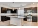 Spacious kitchen featuring dark cabinets, granite countertops, stainless steel appliances, and a center island at 8056 Haywood Estate Ave, Las Vegas, NV 89113