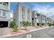 Street view of modern townhomes features desert landscaping, brick-paved driveways, and gray concrete exteriors at 8056 Haywood Estate Ave, Las Vegas, NV 89113