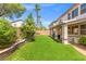 Lush backyard with manicured lawn, stone-edged flower beds, and a covered patio at 8723 Melissa Meadows St, Las Vegas, NV 89131